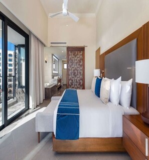 Relax in a spacious room with a large bed, wooden headboard, and a sitting area featuring a table and chairs.