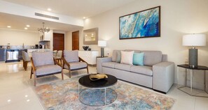 Relax in this stylish living room with a sofa, armchairs, and a coffee table, surrounded by a large abstract painting and a dining area.