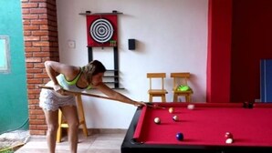 Una mesa de billar con bolas, un objetivo en la pared y una persona jugando.