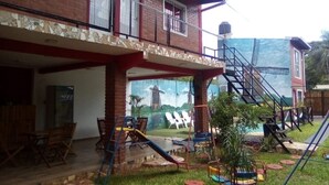 Un edificio de dos plantas con balcón, zona de estar al aire libre y una escalera que conduce a un nivel superior.