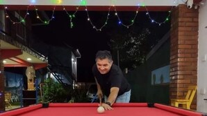 Una mesa de billar con una persona jugando, rodeada de coloridas bolas de billar.