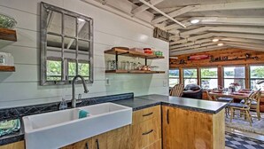 A kitchen with a large window, wooden cabinets, and a built-in sink. - Cozy Lakefront Cabin w/ Sandy Beach & Bunkhouse! (Deerwood)