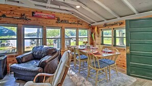 A cabin interior with a leather sofa, dining table, and chairs. - Cozy Lakefront Cabin w/ Sandy Beach & Bunkhouse! (Deerwood)
