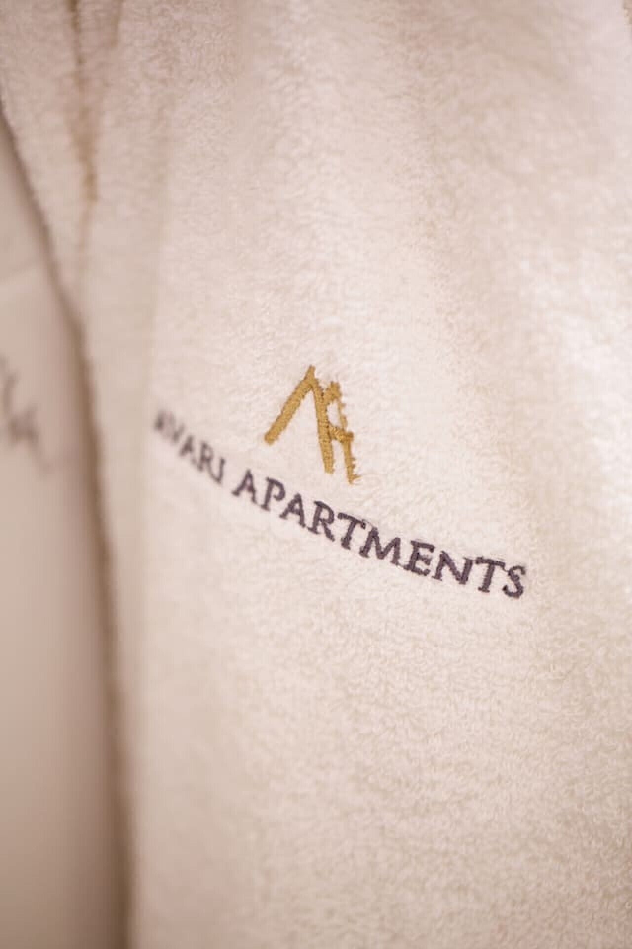 A close-up of a fabric with the logo and name 'MARU APARTMENTS' embroidered on it.