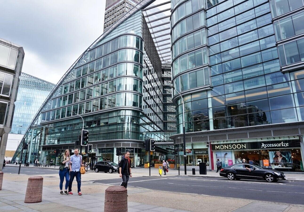Un bâtiment moderne en verre, doté d’une façade incurvée, d’un passage piéton et de boutiques, dont Monsoon et Accessorize.