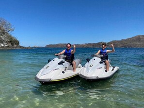 Two people on jet skis in clear water with a hilly landscape in the background. - Freshly Updated 3BR With Pool Walk to the Beach Casa Luz de Luna (Tempate)