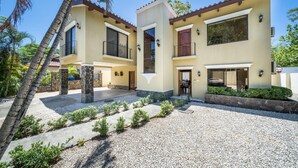 A two-story house with a patio, palm trees, and a clear sky. - Freshly Updated 3BR With Pool Walk to the Beach Casa Luz de Luna (Tempate)