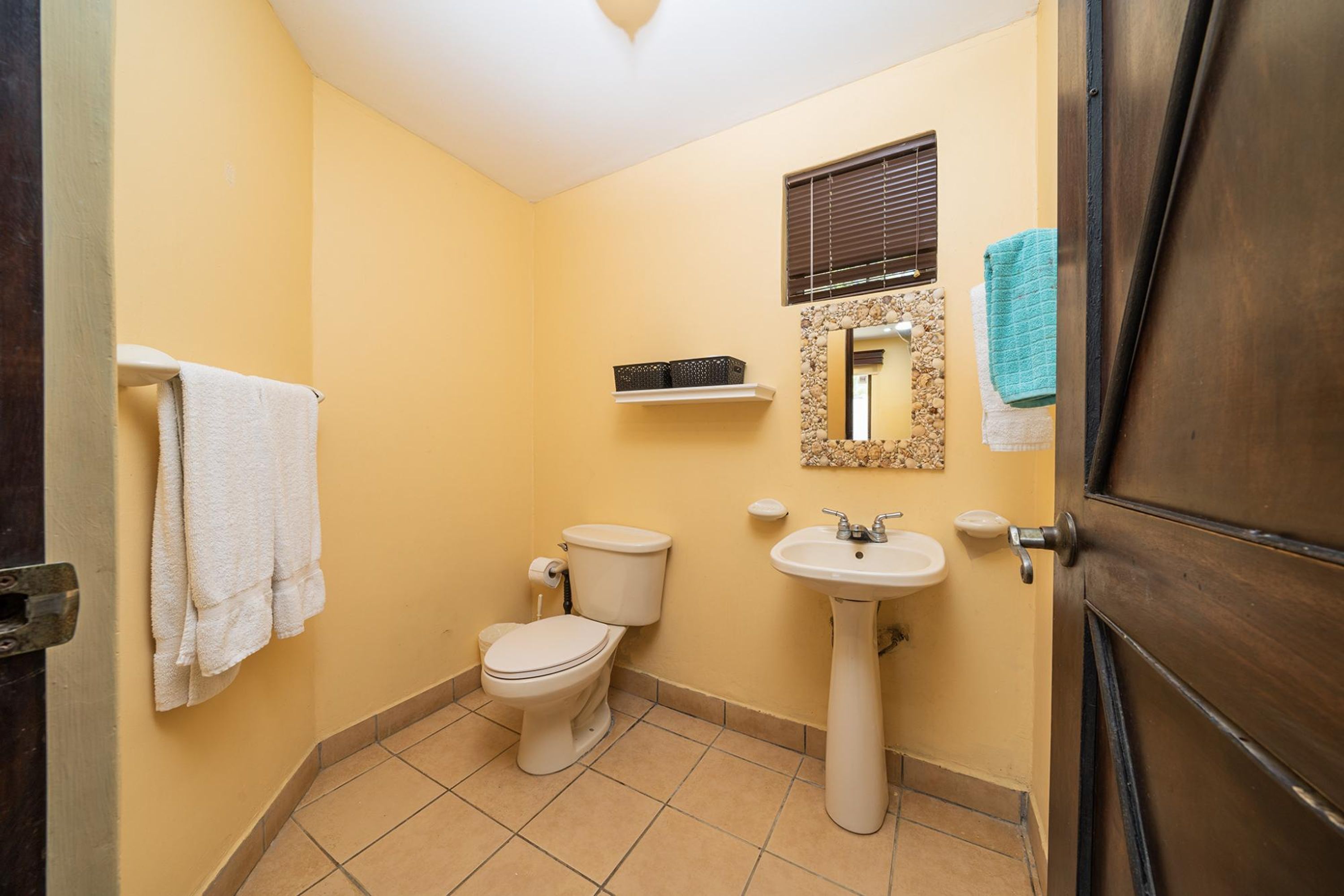 Un baño con inodoro, lavamanos y perchero para toallas.