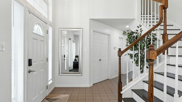 A hallway with white doors, a wooden staircase, and a potted plant.