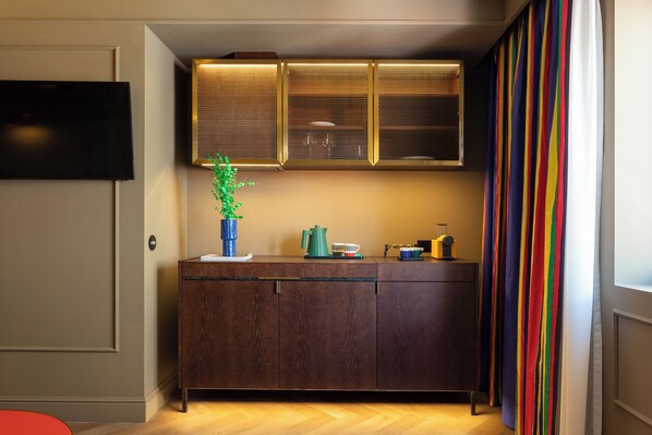 Una cocina moderna con un armario de madera oscura, un televisor de pantalla plana y una ventana con cortinas a rayas.