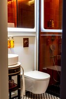 A compact bathroom with a white toilet, a sink with a mirror, and a shower area with a glass door.