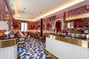 Un'area bar con pavimento decorato, sgabelli da bar e un bancone con diverse bottiglie e barattoli.