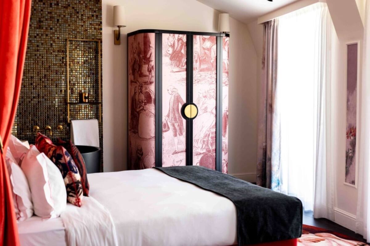 Hotellihuone, jossa on suuri sänky, koristeellinen seinä mosaiikkikuviolla, suuri ikkuna verhoilla ja näkymä ulos.