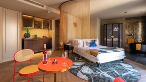 A modern hotel room with a bed, a round table with a bottle and glasses, a chair, and a decorative wall panel. - Upon Angels - Adults Only (Lisbon)