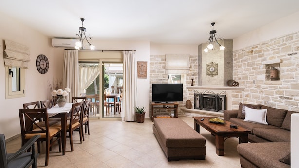 A spacious living room with a fireplace, a television, and a dining area with a view of the outdoors.