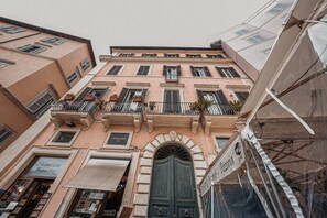 A multi-story building with a central entrance, balconies with railings, and a sign indicating a restaurant. - Navona Charming Balcony (Roma)