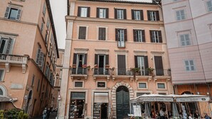 A building with multiple floors, balconies with potted plants, and a storefront with outdoor seating.