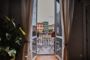 Uma varanda com vista para uma praça pública, com uma fonte e edifícios ao fundo.
