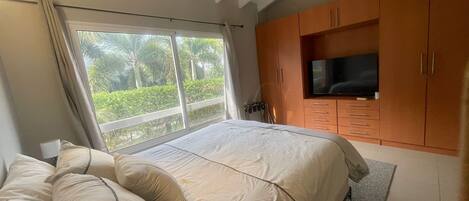 Un dormitorio con cama, televisión y ventana con vistas a zonas verdes.