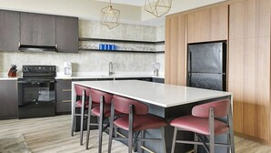 A modern kitchen with a central island, bar stools, a built-in oven, and a refrigerator. - 1BD/Atlanta - Downtown w/Rooftop Pool and Pool Bar! (Atlanta)
