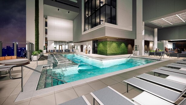 A modern indoor pool with a green wall, lounge chairs, and a cityscape view. - 1BD/Atlanta - Downtown w/Rooftop Pool and Pool Bar! (Atlanta)