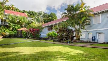 A residential property with a well-maintained lawn, a gazebo, and a variety of tropical plants.
