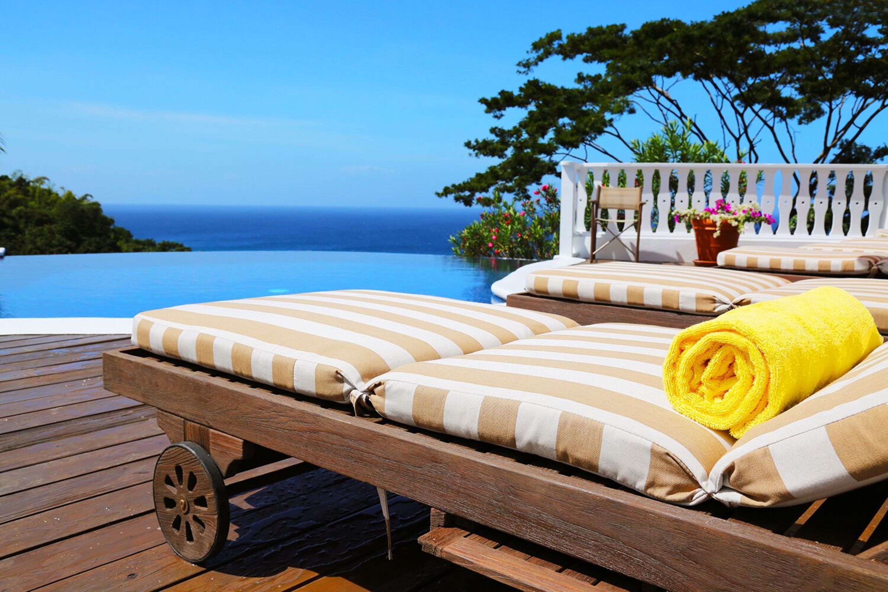 A wooden deck with a lounge chair and a rolled yellow towel.