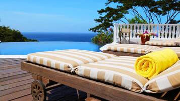 A wooden deck with a lounge chair and a rolled yellow towel.