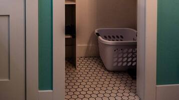 A narrow hallway with a closet, a laundry basket, and a tiled floor.