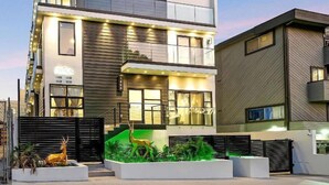A modern two-story building with a balcony, large windows, and a green garden area with a deer sculpture. - 1408 N Poinsettia Pl (Los Angeles)