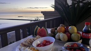 Une table dressée avec des aliments pour le petit-déjeuner, notamment des fruits, du pain et une bouteille de Coca-Cola, offrant une vue panoramique.