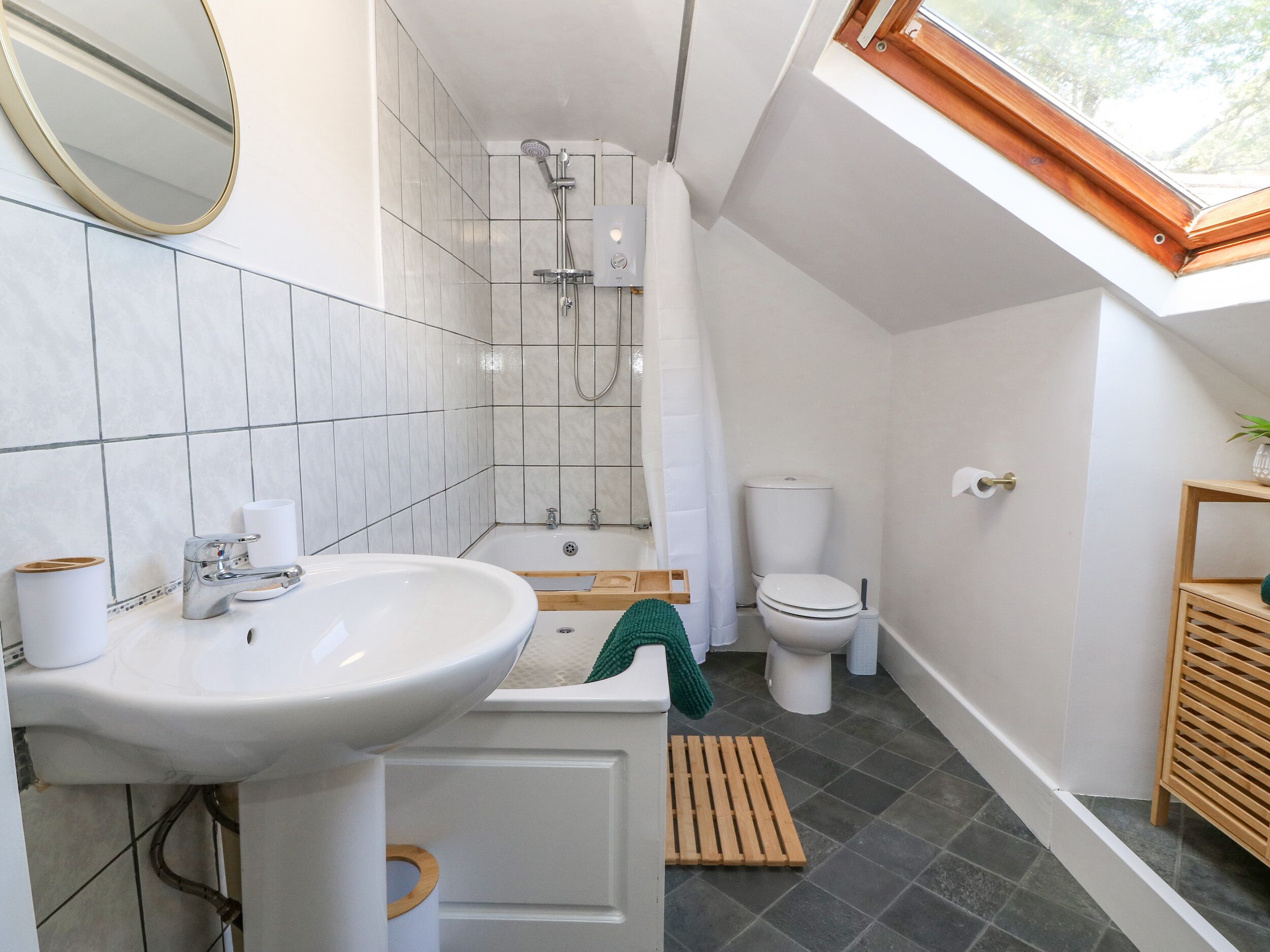 A modern bathroom with a skylight, a bathtub, a toilet, and a sink.