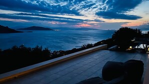 A terrace with a view of the sea and distant mountains at dusk. - Minimalist, new condo with beautiful sea and mountain views (Aegina)