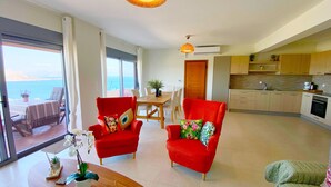 A modern living room with a dining area, a kitchen, and a view of the sea. - Minimalist, new condo with beautiful sea and mountain views (Aegina)