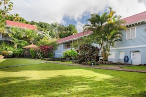 A residential property with a well-maintained lawn, a small garden with tropical plants, and a red-roofed house. - Experience Local Culture: Nutmeg Superior Room at Mount Edgecombe Boutique Hotel (Victoria)