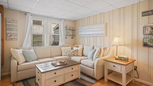 Ein gemütliches Wohnzimmer mit einem beigen Sofa, einem Holztisch und einem Nachttisch mit Lampe.