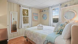 Ein Schlafzimmer mit Bett, Nachttisch, Spiegel und einem Fenster mit Jalousien.