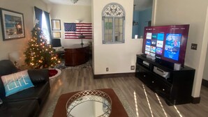 Una sala de estar con ventilador de techo, árbol de Navidad, televisor y chimenea.