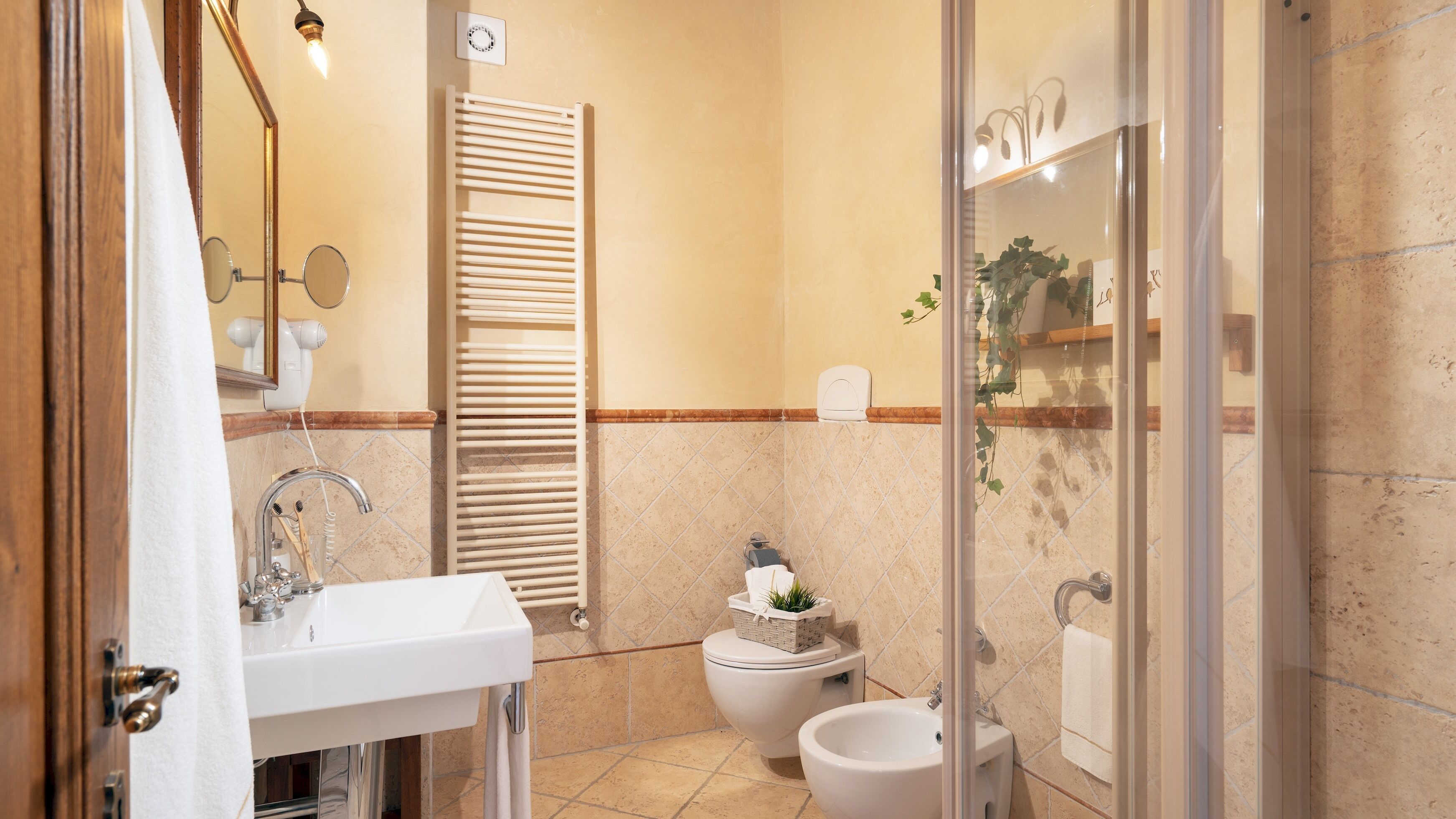 Een badkamer met een wastafel, toilet, bidet en een handdoekhouder.
