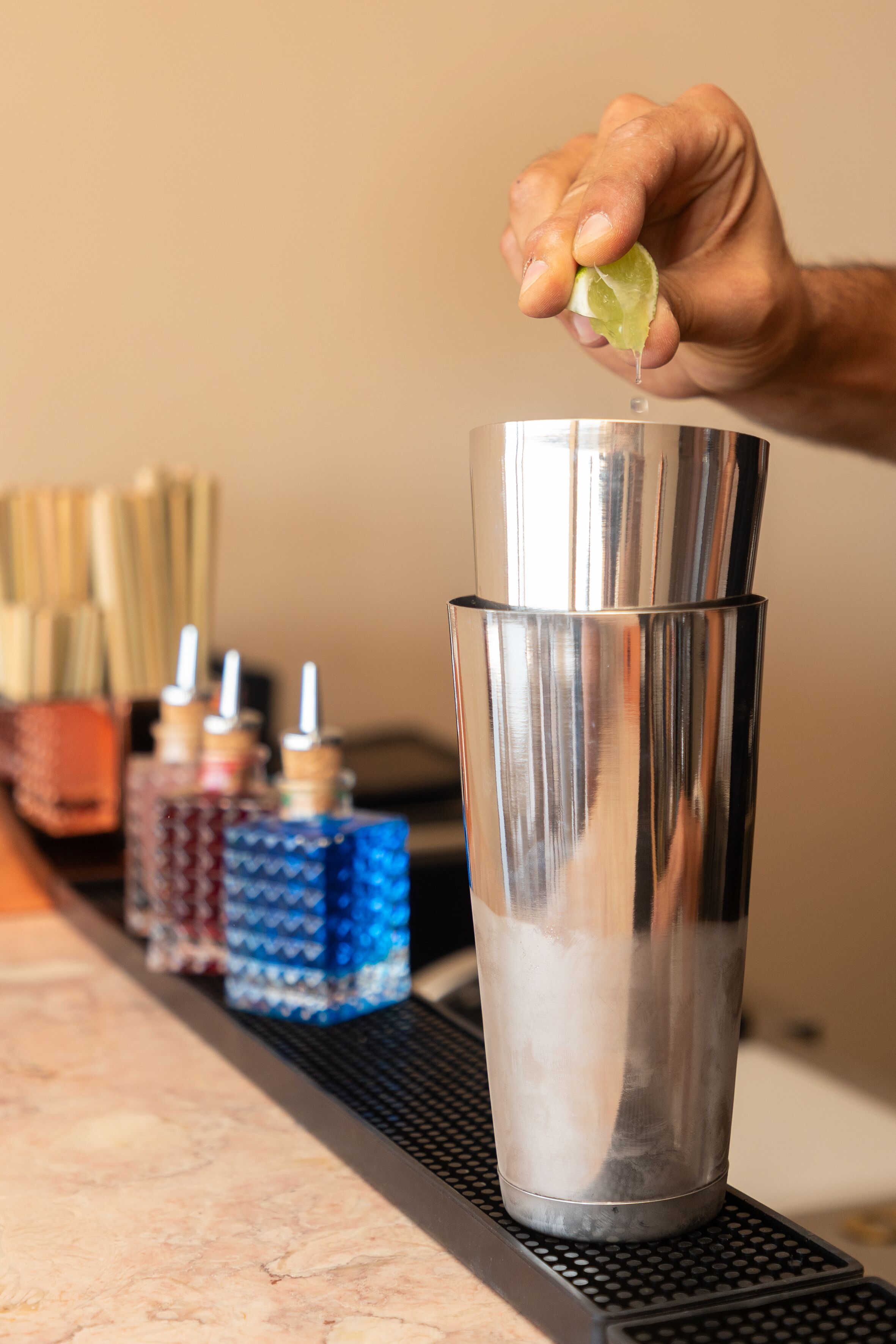 A hand squeezing a lime into a shaker.
