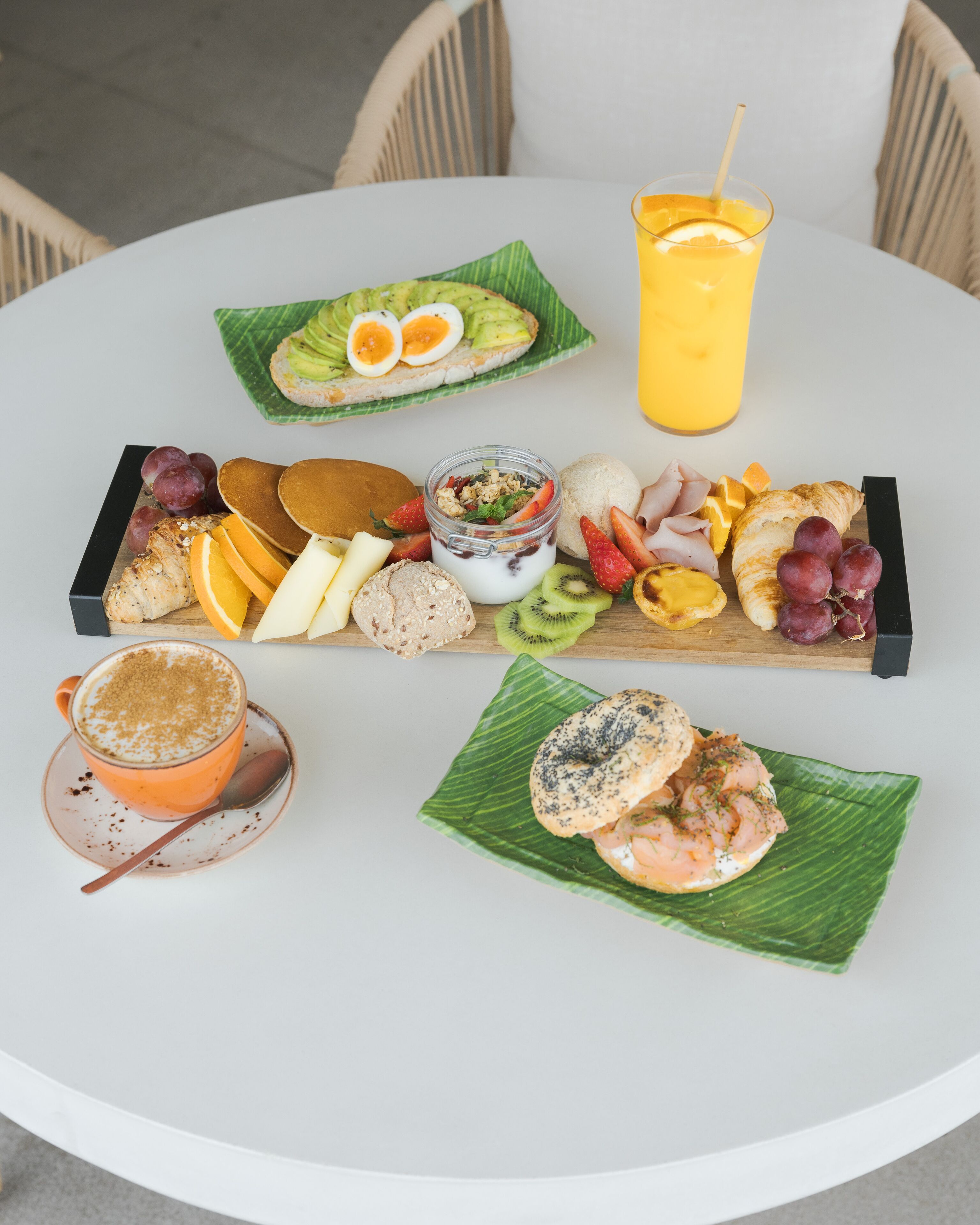 A round white table with a breakfast spread including eggs, toast, fruit, and a drink.