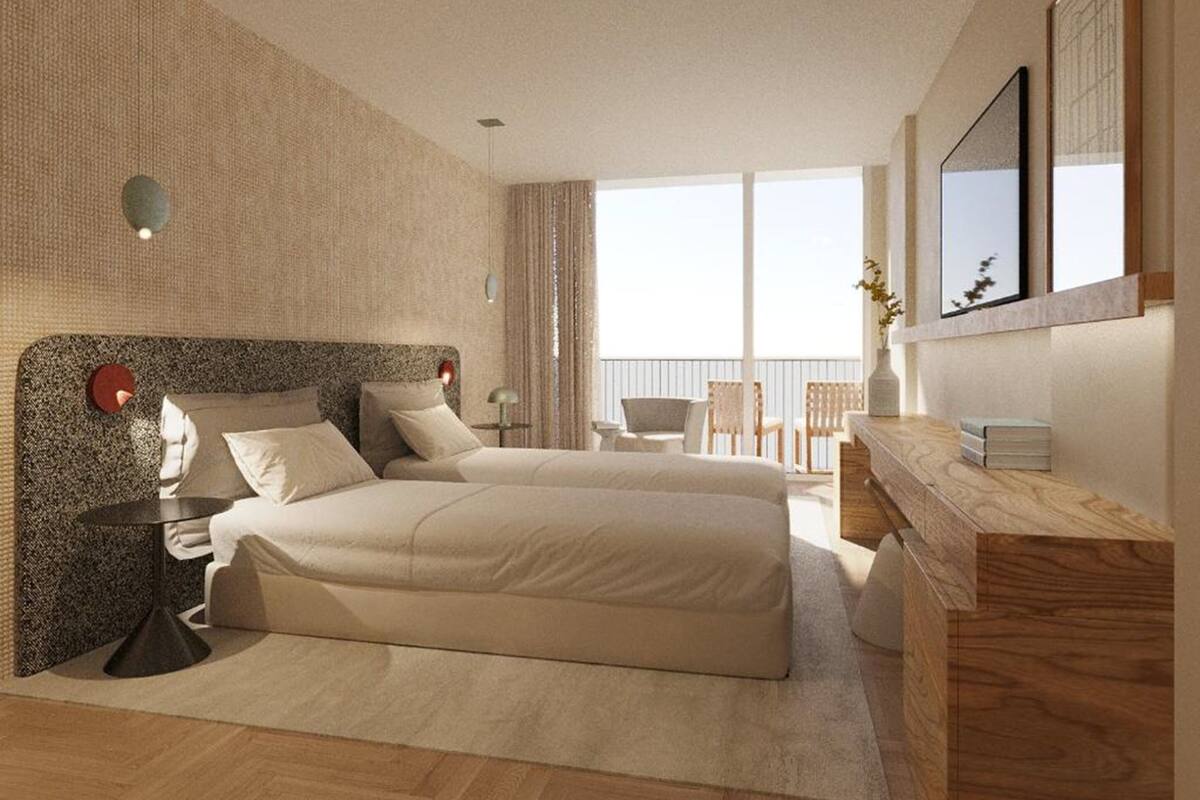 Een moderne hotelkamer met een groot bed, een bureau en een balkon met stoelen.