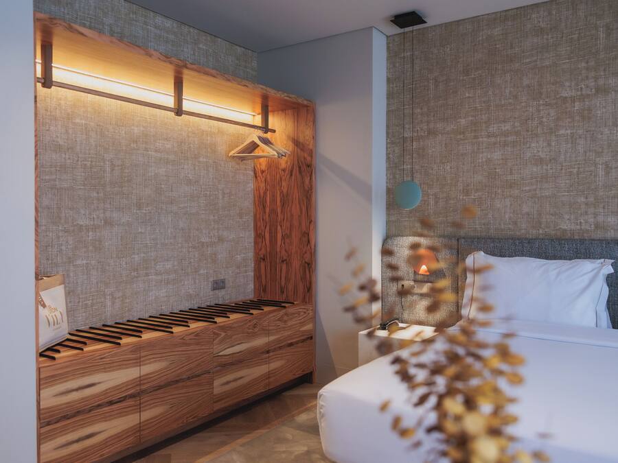A modern bedroom with a wooden bench, a bedside table, and a hanging light fixture.