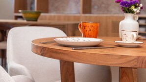 A dining table with plates, a cup, and a vase with flowers. - Upon Vila Alcochete Hotel (Alcochete)