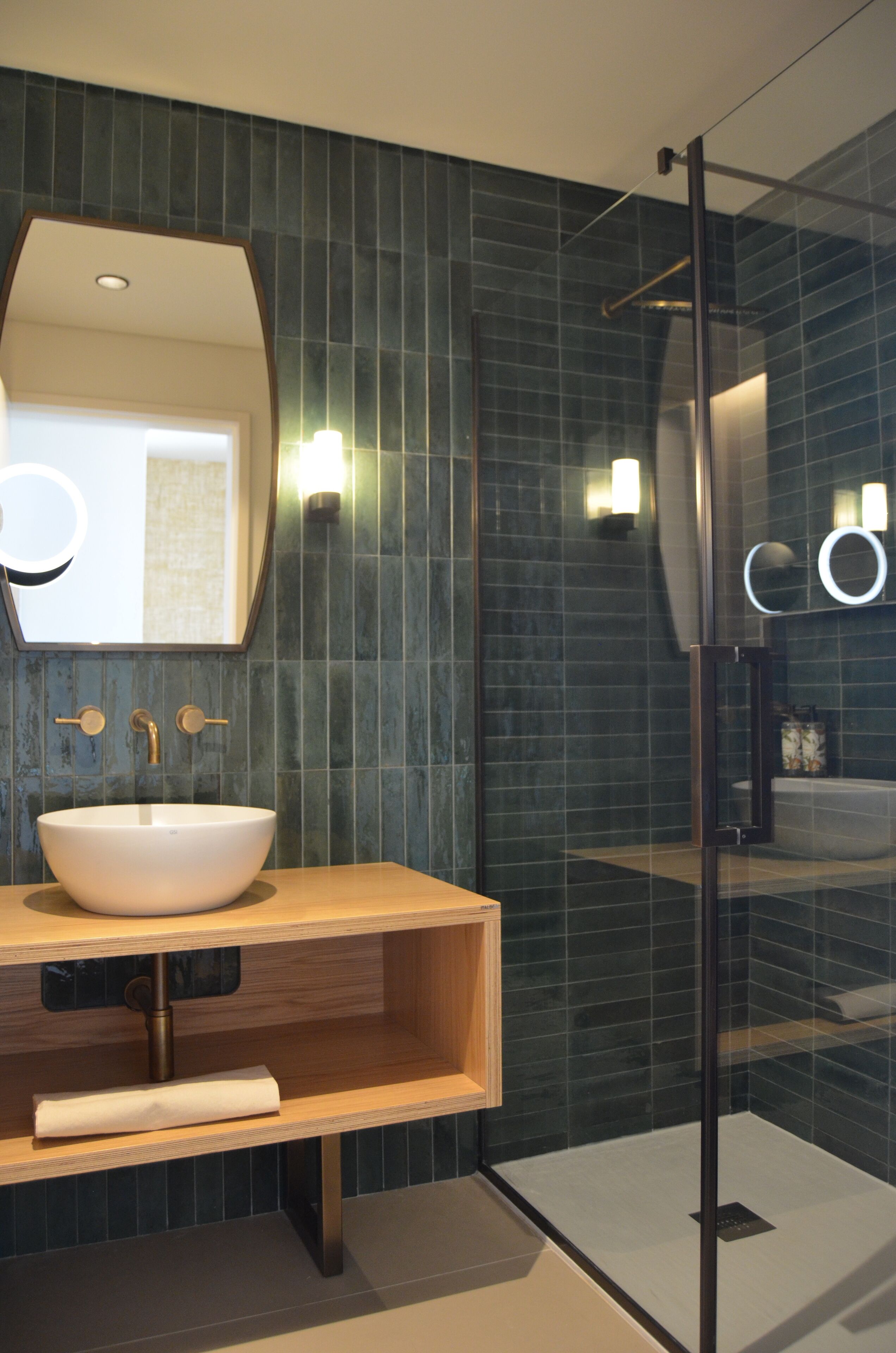A modern bathroom with a large mirror, a white sink, and a glass shower enclosure.
