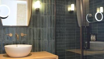 A modern bathroom with a large mirror, a white sink, and a glass shower enclosure.