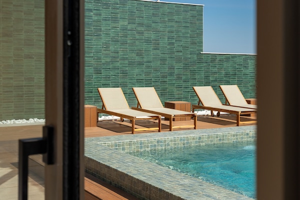 Una piscina al aire libre, sillones reclinables de piscina