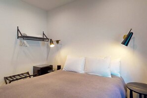 A bedroom with a bed, bedside tables, a hanging shelf, and a lamp. - Downtown Gold Mine (Nevada City)