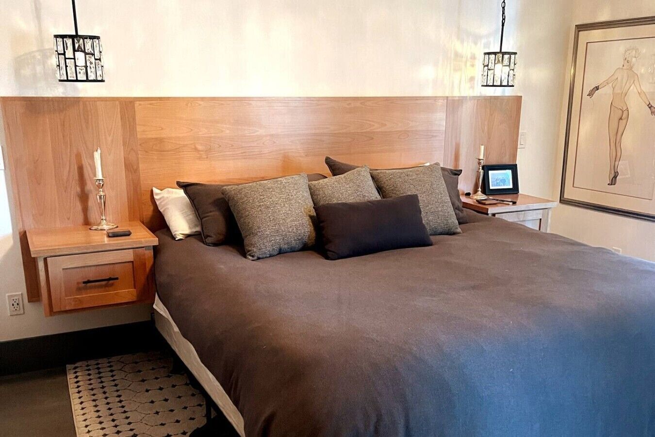 A bedroom with a large bed, a wooden headboard, bedside tables with lamps, and a framed artwork on the wall.