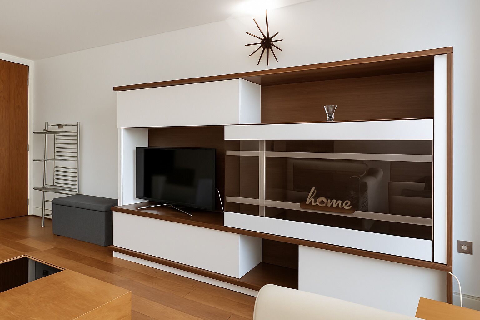 A modern living room with a built-in TV, a glass-fronted storage unit with the word 'home' on it, and a star-shaped light fixture.